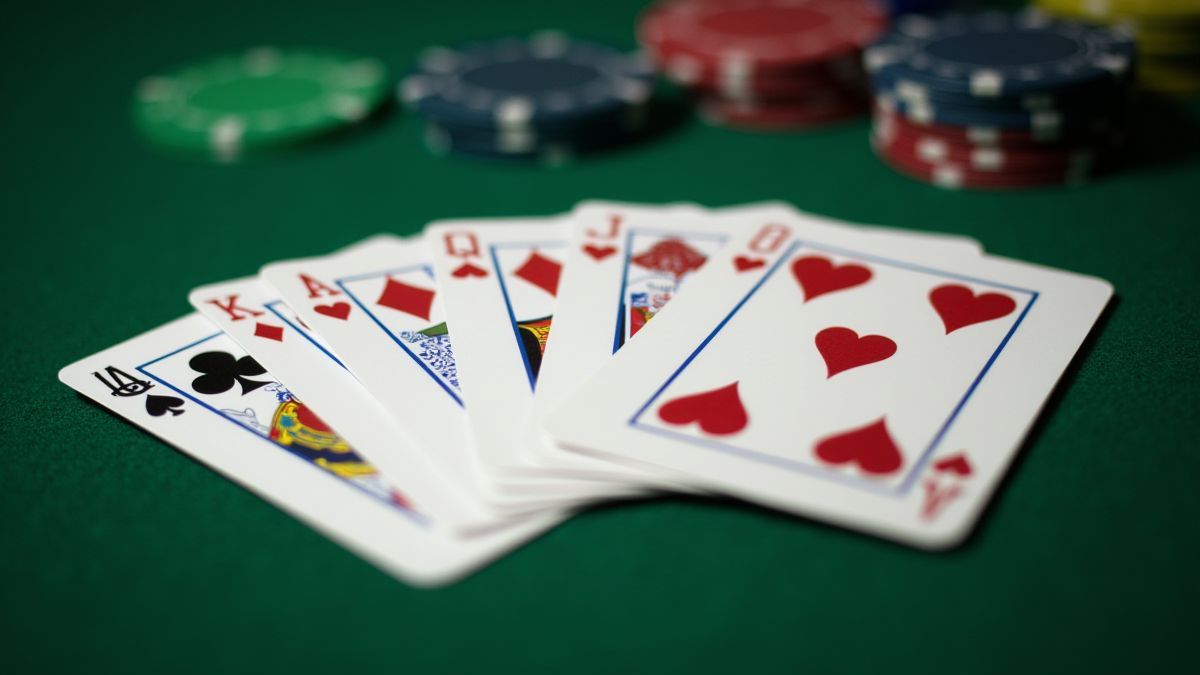 Kartenspiel und Pokerchips auf einem grünen Tisch.