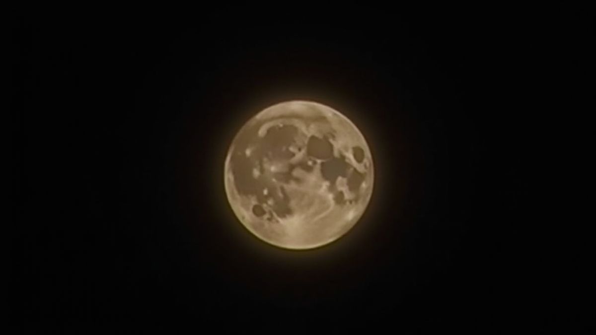 Een heldere volle maan in een donkere en dramatische lucht.