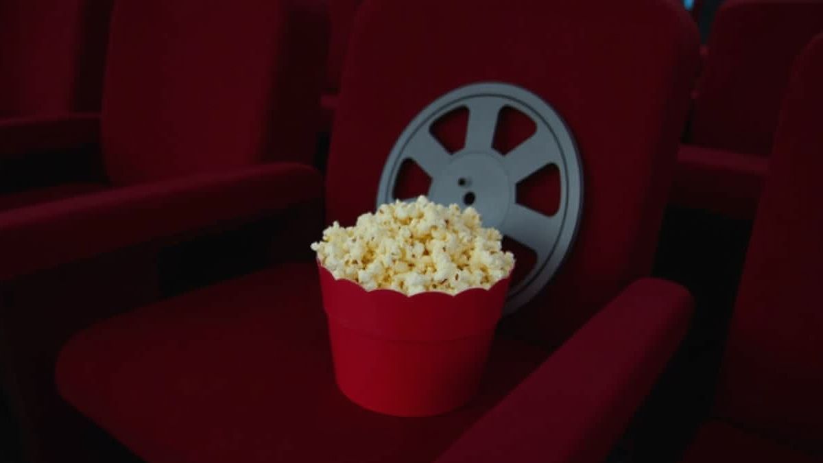 Pop-corn et rouleaux de film sur un siège de cinéma.