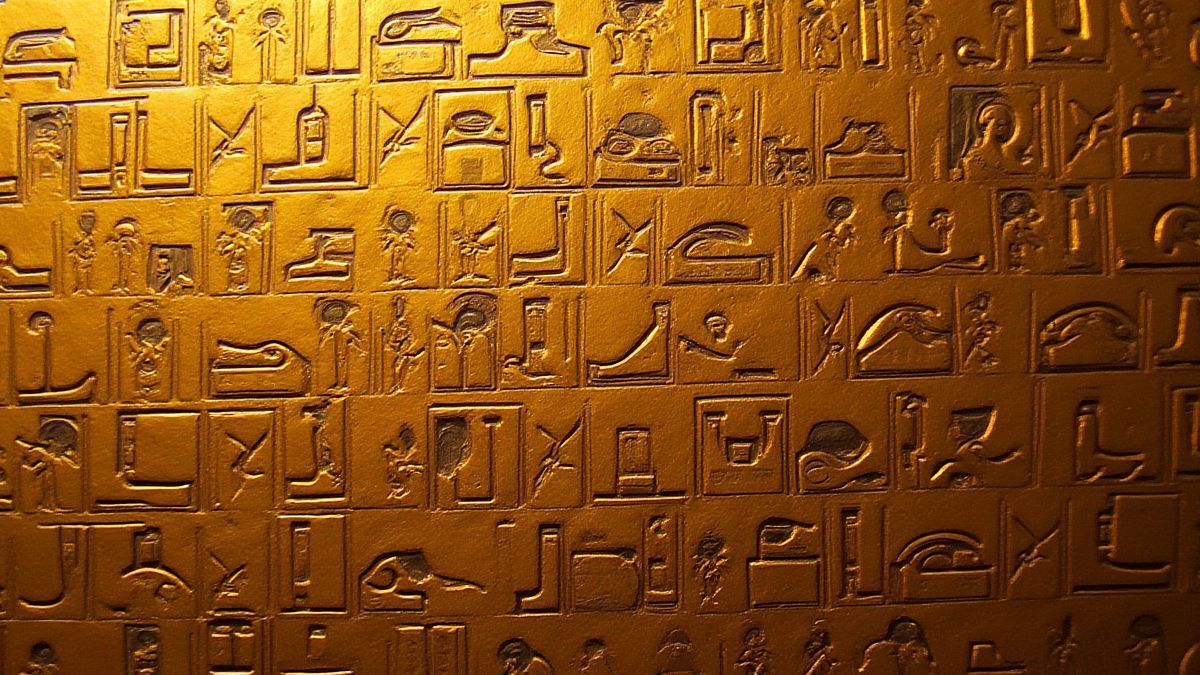 Jeroglíficos egipcios en colores dorados vibrantes.