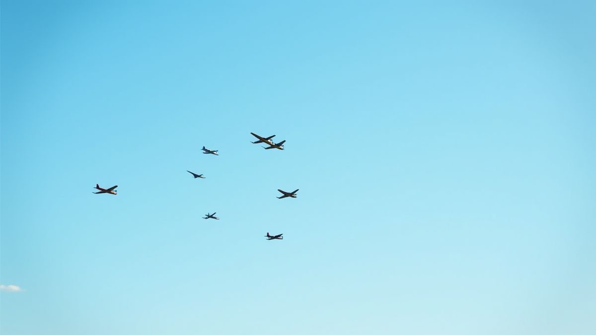 Aviones vintage volando en formación en un cielo azul soleado.